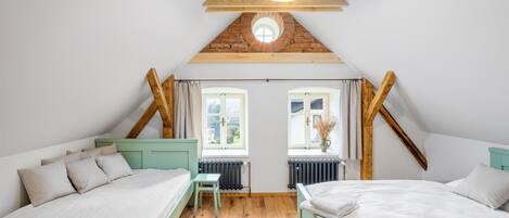 A bedroom with two beds, a small table, and a window with curtains.