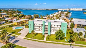 A multi-story hotel with a pool, located near a marina with boats.