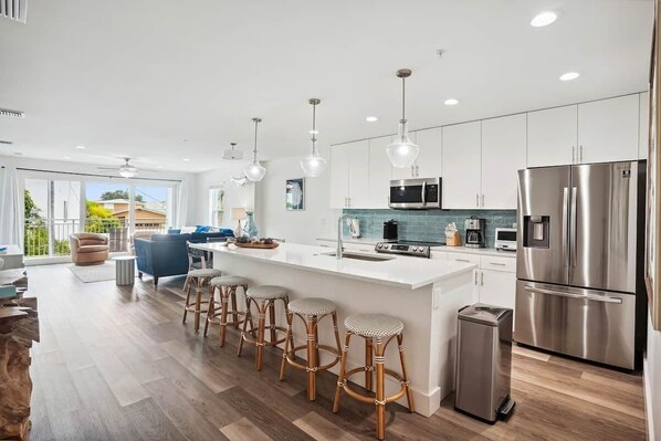 A modern kitchen with a central island, stainless steel appliances, and a dining area with bar stools.