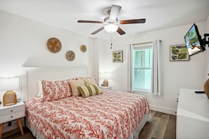 A bedroom with a bed, a ceiling fan, a window, and wall decorations. - Modern Coastal Condo-4 Minute Walk to the Beach (Madeira Beach)
