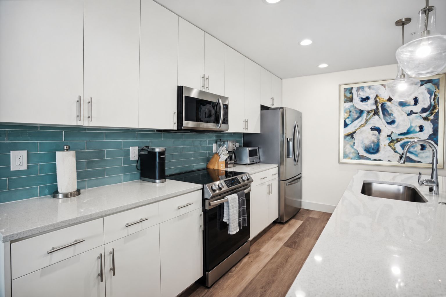 A modern kitchen with white cabinets, a stainless steel refrigerator, a microwave, and a coffee maker.