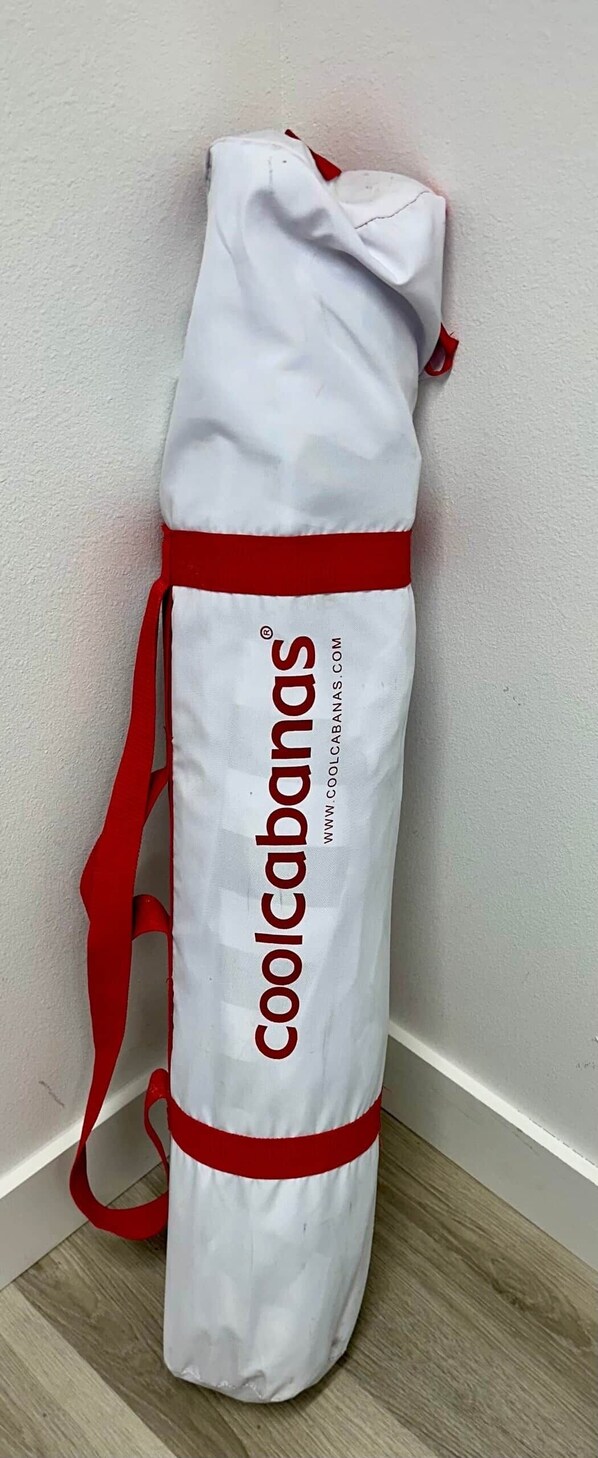A white bag with red accents and the text 'coolcabanas.com' on a plain wall.