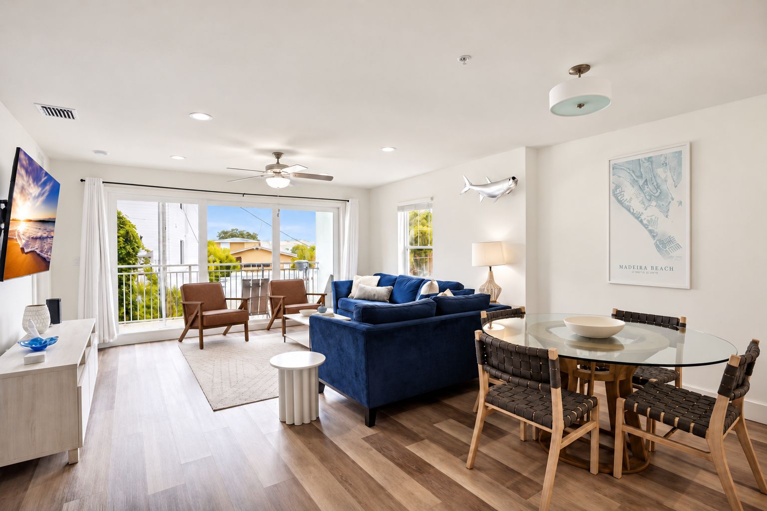 Ein modernes Wohnzimmer mit einem blauen Sofa, einem Glastisch und einem Balkon mit Blick.