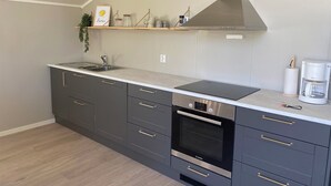 Una cocina moderna con armarios grises, un horno de acero inoxidable y una campana extractora integrada.