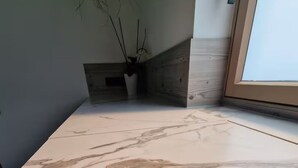 A marble countertop with a plant in a white pot. - Barrier-free enjoyment in Unterallgäu, modern apartment with style and comfort   (Oberschönegg)