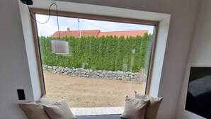 A room with a built-in bench with cushions, a small round table, and a TV mounted on the wall. - Barrier-free enjoyment in Unterallgäu, modern apartment with style and comfort   (Oberschönegg)