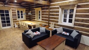 L’intérieur d’une cabane en rondins comprend un coin repas, deux canapés, une table basse et une grande fenêtre.