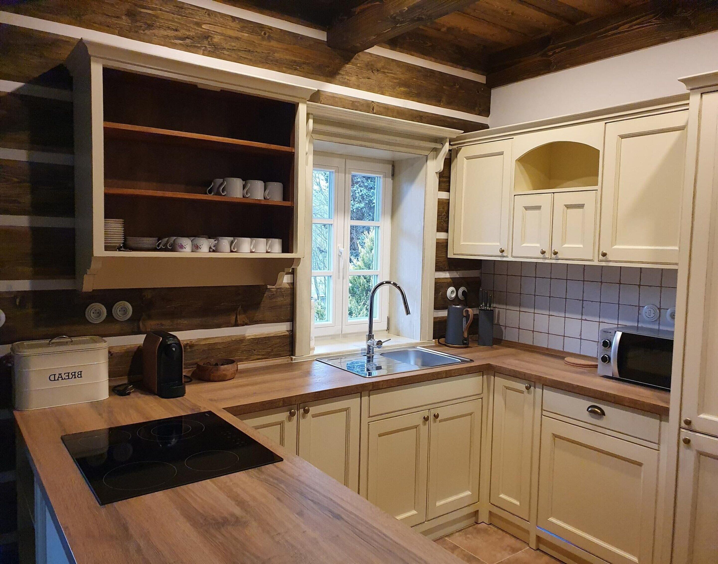 Eine Küche mit Holzausstattung, einem Backofen, einem Spülbecken und einem Fenster mit Blick auf Grünflächen.