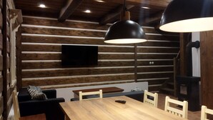 Un intérieur rustique avec des éléments en bois, notamment une table à manger en bois, des chaises et des luminaires suspendus.