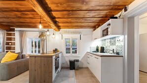 A modern kitchen with wooden ceiling beams, a central island, and white cabinetry.