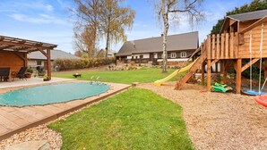 A backyard with a wooden deck, a swimming pool, and a slide.
