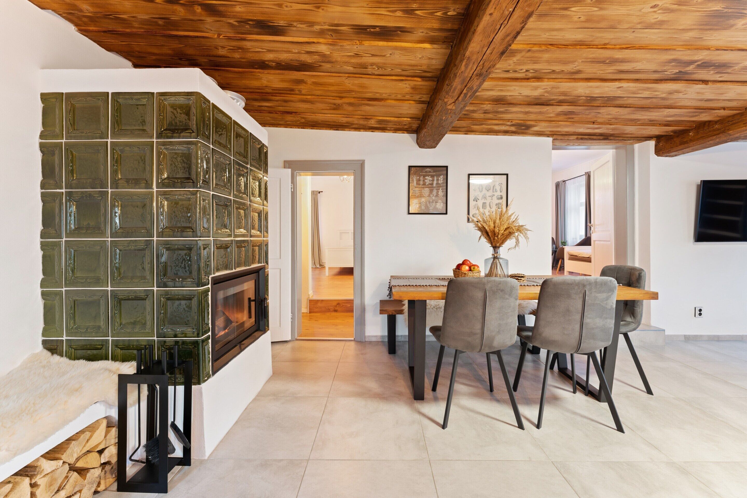 A modern kitchen with a built-in stove, a dining area with a wooden table and chairs, and a rustic wooden ceiling.