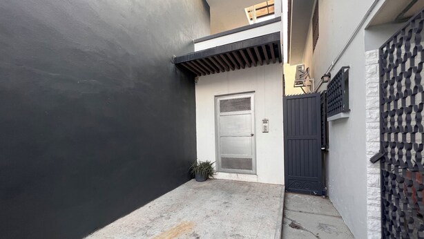 A narrow alleyway with a black wall on one side, a grey door with a metal grill, and a patterned gate on the other. - Charming 1-bedroom apartment in marvelous Monterrey with AC, WiFi (Monterrey)