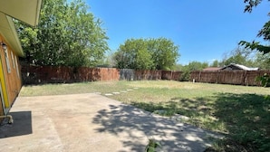 A concrete patio area with a wooden fence in the background.