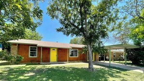 A single-story house with a yellow front door, a covered porch, and a well-maintained lawn.