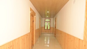 Un largo y estrecho pasillo con paredes de madera y piso pulido, que conduce a una puerta con un ventanal al final.