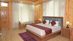 Una habitación con paneles de madera, una cama grande, dos mesitas de noche con lámparas, una silla y un armario de madera.