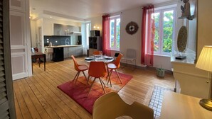Una cucina moderna con mobili grigi, un'isola centrale e un'area pranzo con sedie arancioni e un tappeto rosso.