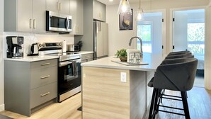 A modern kitchen with grey cabinets, stainless steel appliances, and a central island with bar stools.