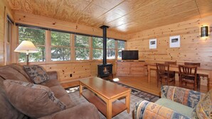 A cozy cabin interior with a sofa, a coffee table, a TV, and a fireplace. - Rustic One Bedroom Cabin (Mazama)
