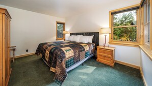 A bedroom with a bed, two bedside tables, a window, and a door.