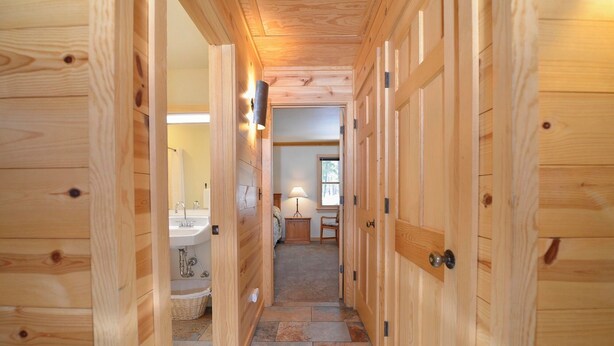 A wooden hallway with a sink, a chair, and a lamp.