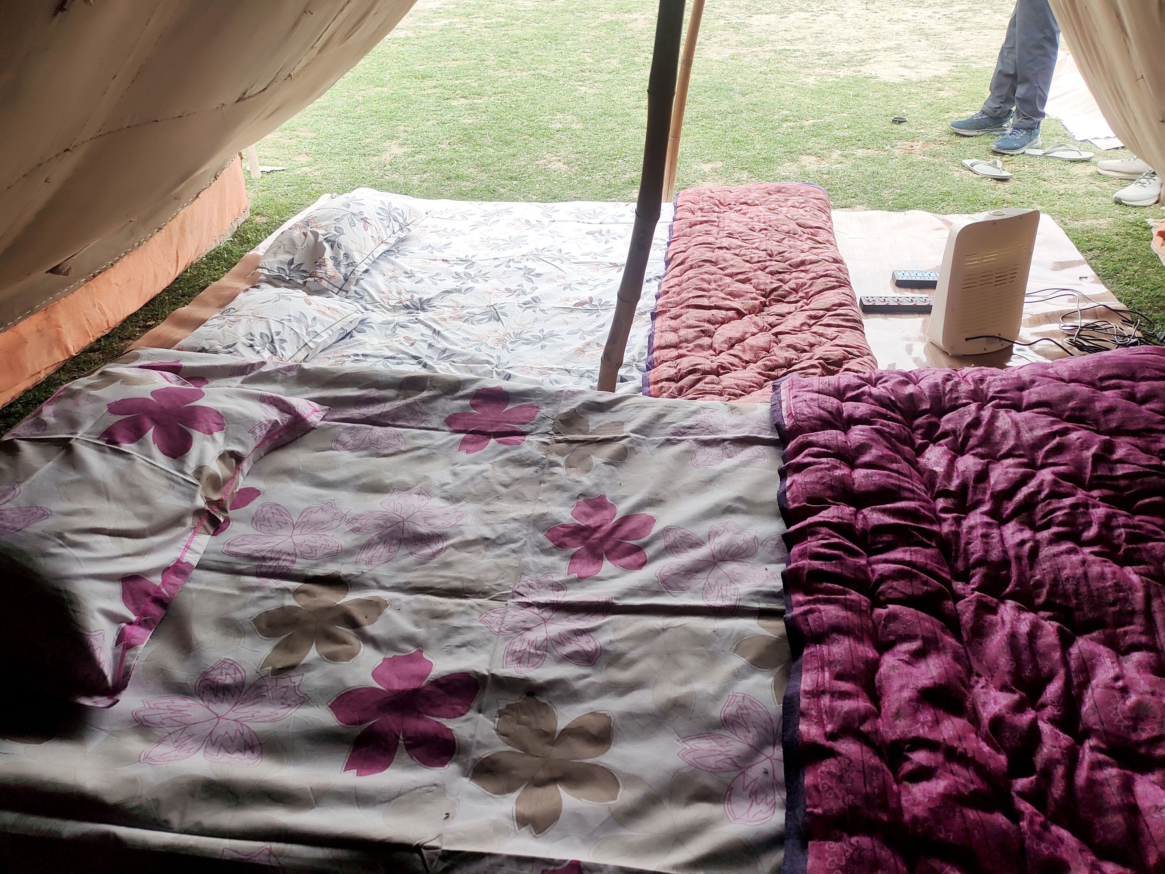 Uma cama com roupa de cama florida e em cores sólidas, um controle remoto e um alto-falante sobre uma mesa.