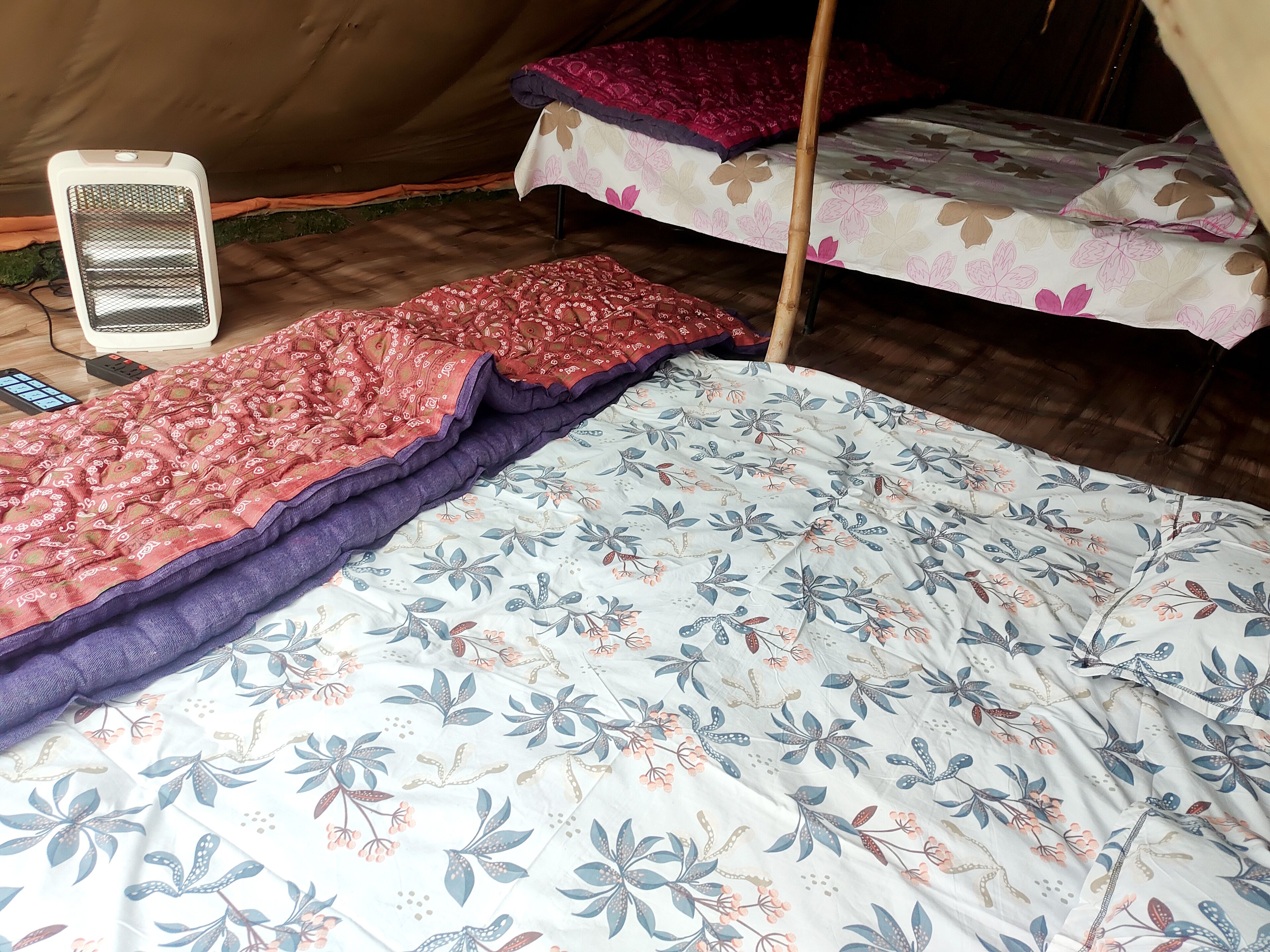 A tent with two beds, each covered with floral-patterned bedding.