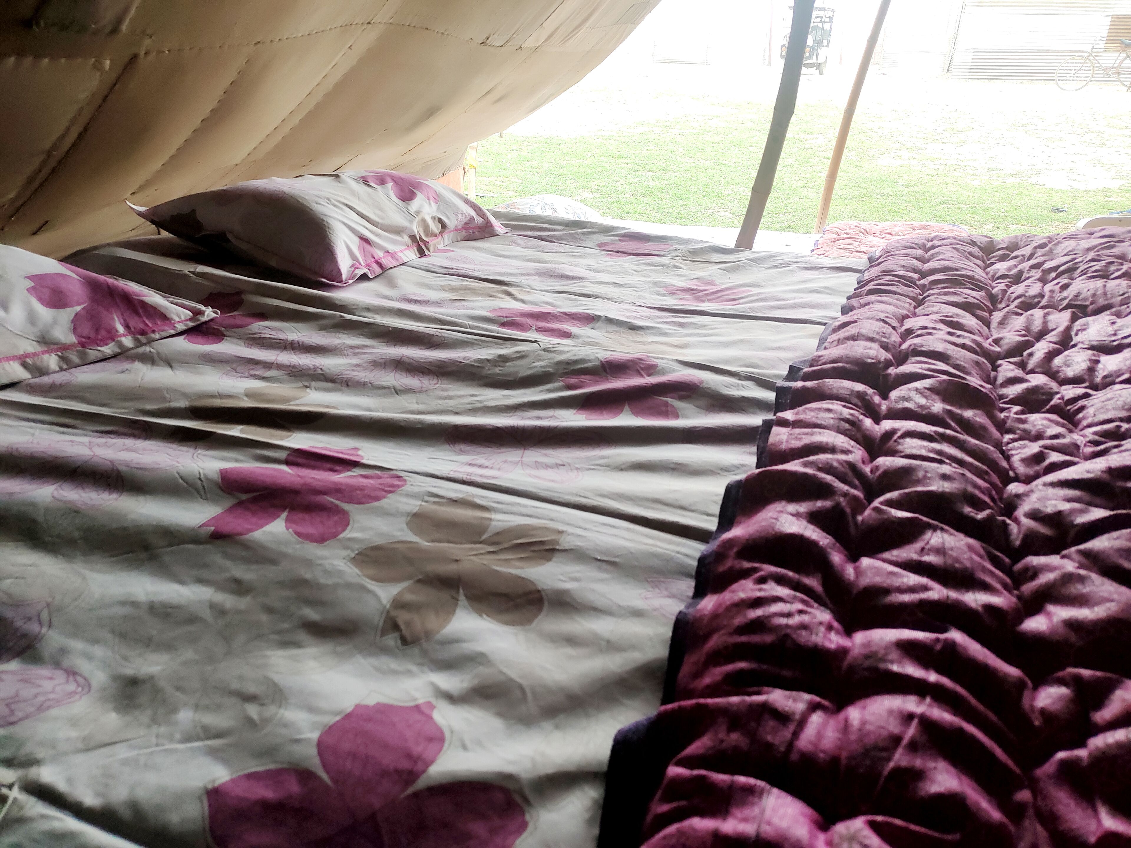 Ein Bett mit floraler Bettdecke und einer violetten Decke.