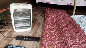 Une chambre avec un lit, un radiateur et une multiprise.