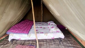 Une tente avec un lit à l’intérieur, dotée d’un poteau en bois au centre.