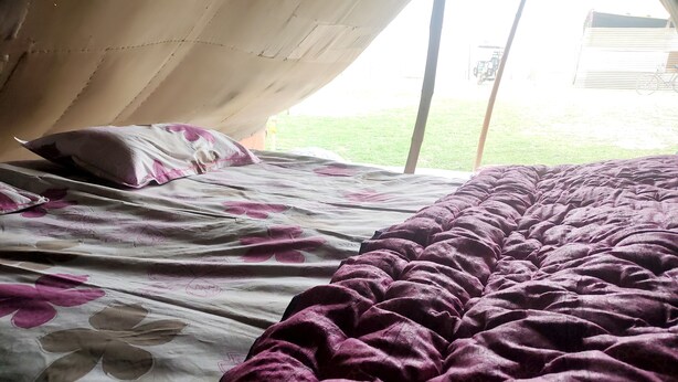 Un lit recouvert d’une couvre-lit à motifs floraux et d’un plaid violet.