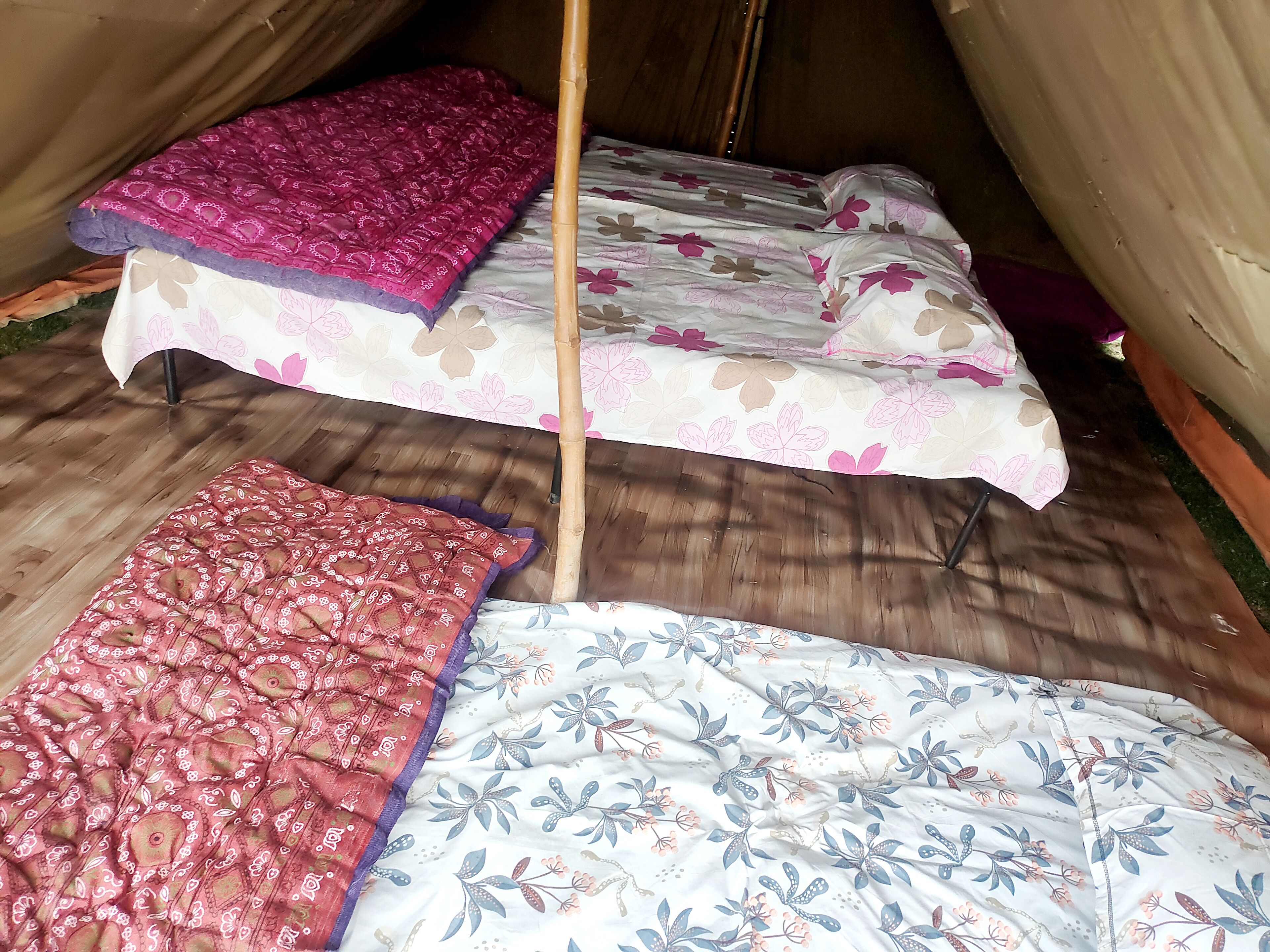 Een tent met twee bedden, elk met een bloemenprintdeken.