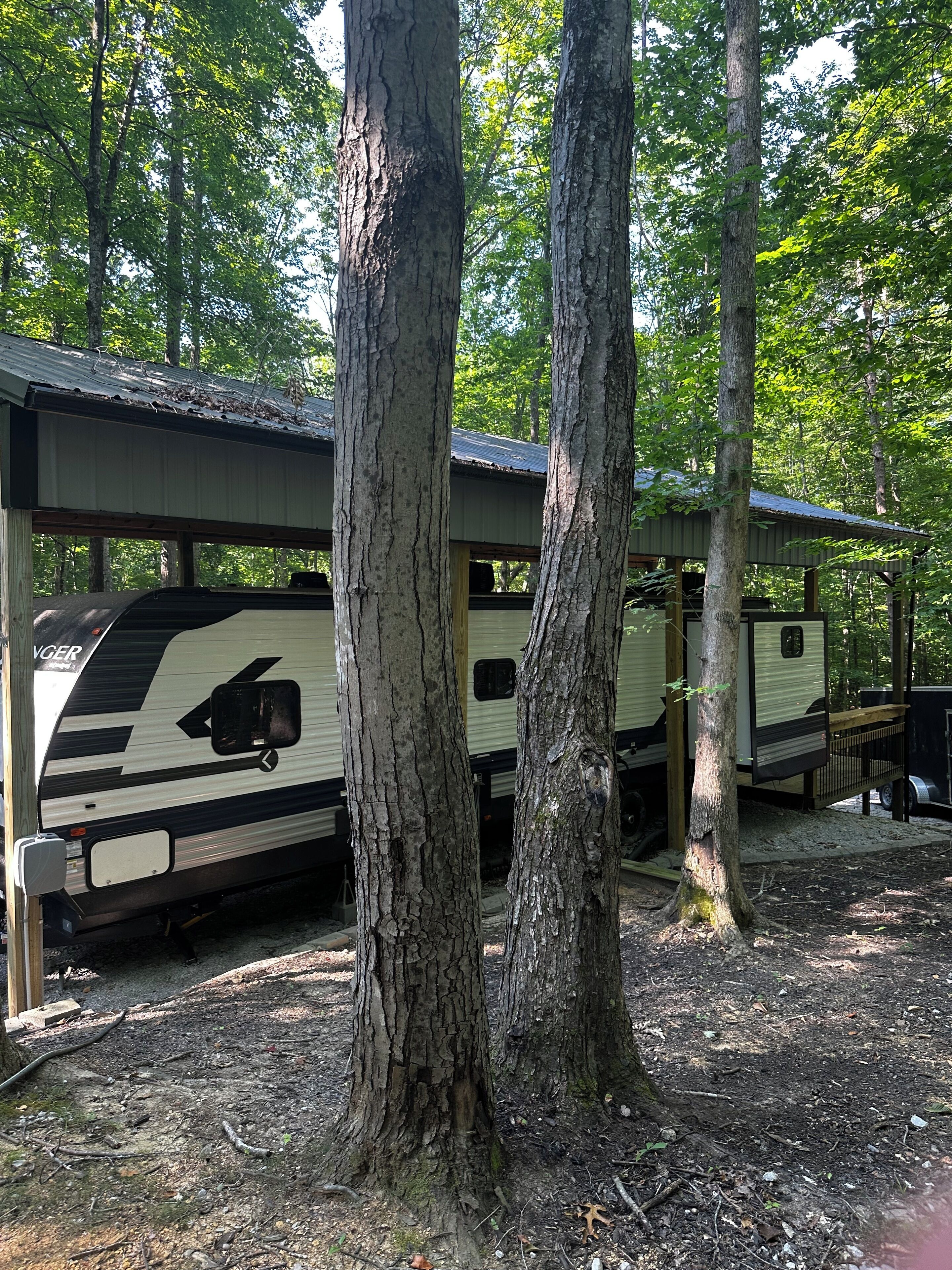 Een RV-camping met meerdere campers onder houten overkappingen.