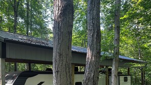 Un terrain de camping pour véhicules récréatifs où de nombreux véhicules sont stationnés sous des abris en bois.