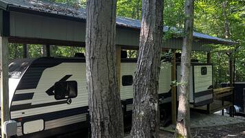 Een RV-camping met meerdere campers onder houten overkappingen.