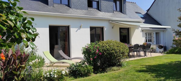 A modern house with a patio, outdoor seating, and a barbecue area.