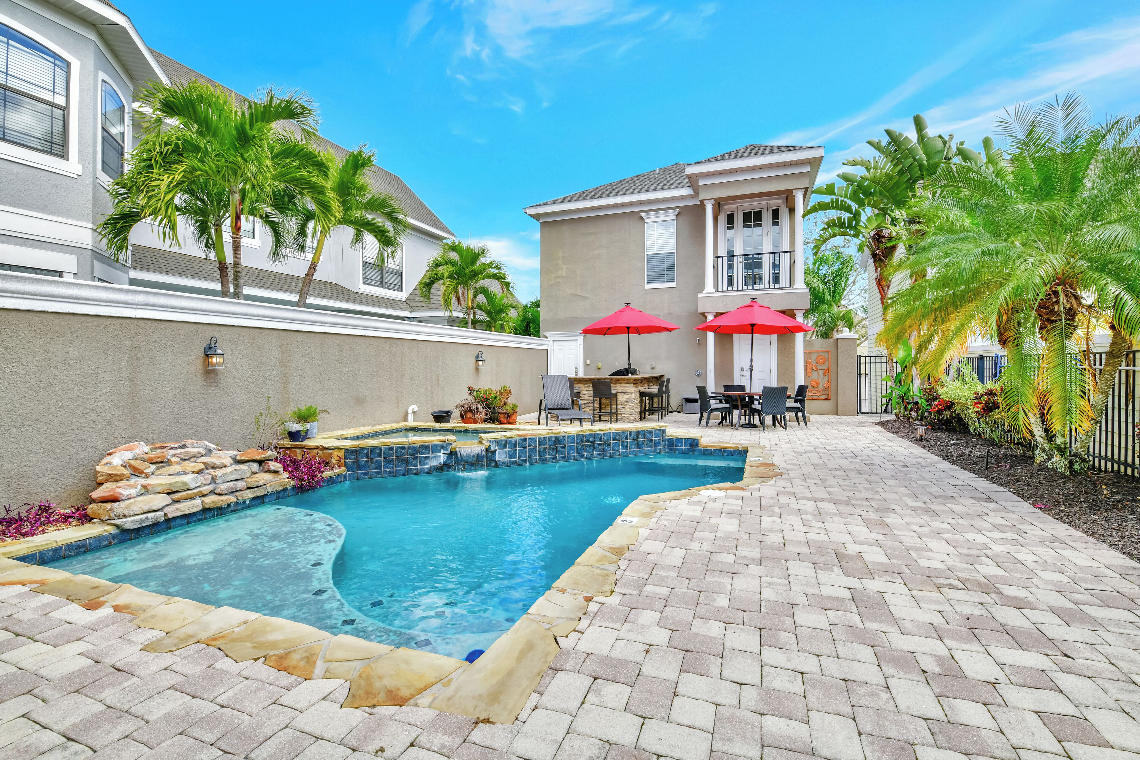 A swimming pool with a stone border, surrounded by a brick patio.