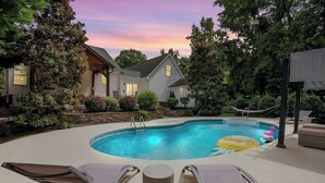 A backyard with a swimming pool, lounge chairs, and a house. - Luxury Retreat & Heated Pool Downtown Simpsonville (Simpsonville)