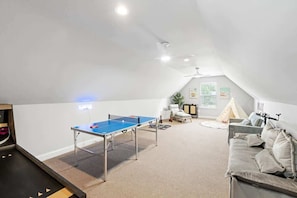Une pièce avec une table de ping-pong, un canapé, une tente et un ventilateur de plafond.