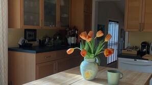 A kitchen with wooden cabinets, a central island with a vase of flowers, and a hanging light fixture. - Beautiful Nantucket summer escape,  3 bed house, quiet office, central location  (Nantucket)