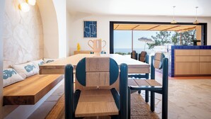 A modern dining area with a long table, cushioned seating, and a view of the sea through large windows. - 180° sea view villa, renovated in 2024, a little paradise in Rayol Canadel (Rayol-Canadel-sur-Mer)