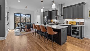 Una cocina moderna con una isla central, armarios oscuros e iluminación colgante.