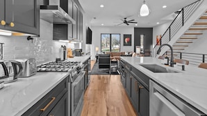 Una cocina moderna con una isla central, electrodomésticos de acero inoxidable y vistas al salón.