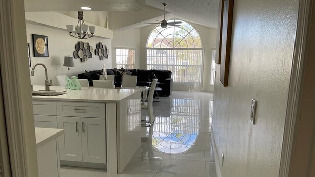 A spacious kitchen with white cabinets, a central island, and a dining area with a black sofa.