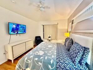 A hotel room with a bed, a TV, a desk, a chair, and a window with blinds. - Grand Superior Grove 4BR Home Near Disney (Davenport)