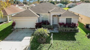 A residential house with a garage, a front porch, and a well-maintained lawn.