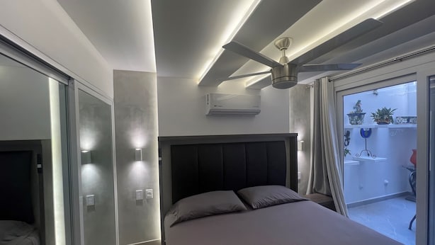 A modern bedroom with a bed, a ceiling fan, and a view of the outside balcony. - Heart of Zona Romantica! 2BD/2Baths, 10 Sec. Walk Beach & Malecon! Quiet Street. (Puerto Vallarta)