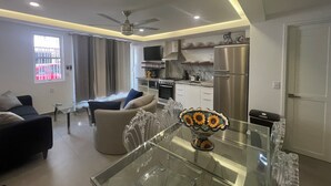 A modern living room with a glass dining table, a sofa, and a TV. - Heart of Zona Romantica! 2BD/2Baths, 10 Sec. Walk Beach & Malecon! Quiet Street. (Puerto Vallarta)