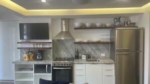 A modern kitchen with a built-in oven, microwave, and gas stove. There is a stainless steel refrigerator and a flat-screen TV mounted on the wall. - Heart of Zona Romantica! 2BD/2Baths, 10 Sec. Walk Beach & Malecon! Quiet Street. (Puerto Vallarta)